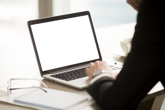 Businessman wearing suit using pc laptop with mock up white blank screen, copy space for text, advertising product or service on monitor, business products ads, web search, close up, focus on screen