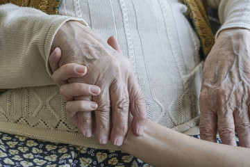 wrinkled hand holding a younger hand