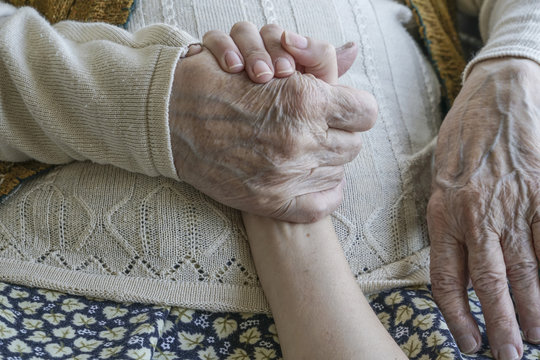 wrinkled hand holding a younger hand