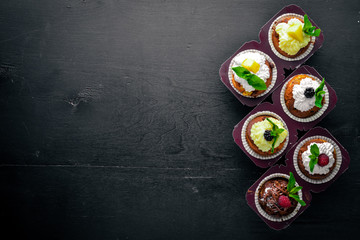 Cakes with fresh fruits and cream filling. On a wooden background. Top view. Free space for text.