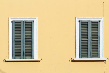 Fototapeta na wymiar Closed shutter windows on a yellow building