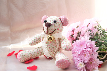 Teddy Bear and dry flower on wooden background.