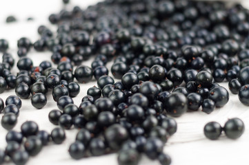 Many fresh ripe blackcurrant scattered on old white rustic wooden planks