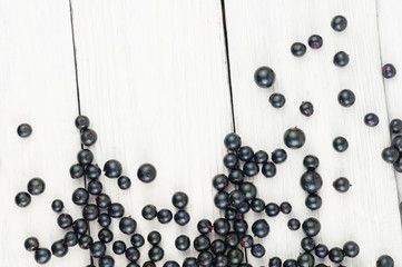 Many fresh ripe blackcurrant scattered on old white rustic wooden planks