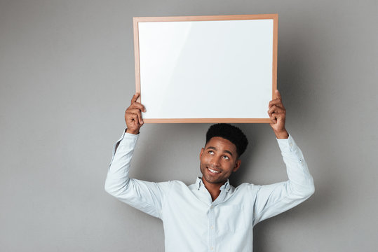 Smiling Young African Man Holding Blank Board Above His Head