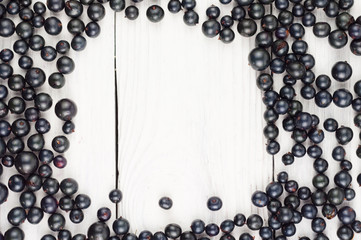 Many fresh ripe blackcurrant scattered on old white rustic wooden planks