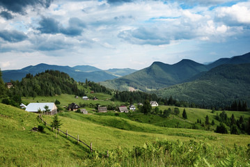 Fototapeta na wymiar Carpathian mountains summer landscape with cloudy sky and village, natural summer travel background