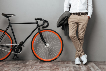 Dressed half mens body standing near a bicycle