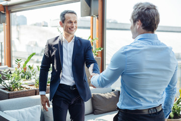 Positive delighted businessmen greeting each other