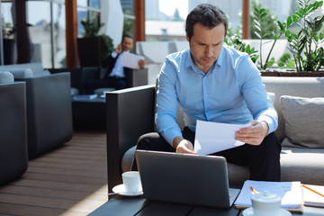 Smart serious businessman studying documentation