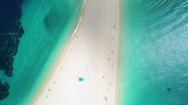 Aerial view of people swimming and sunbathing on Zlatni Rat, on the island of Brac, Croatia. Tilting up the image.