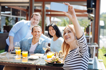 Joyful nice woman taking a photo of her friends