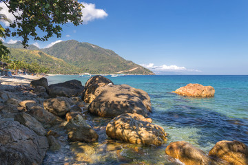 Seascape of beach with transparent sea, blue sky, palms and boats.Taken at Puerto Galera, Mindoro island, Philippines, popular tourist and diving spot. Reminds of heaven or travel of dream.