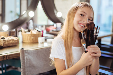 Adorable little girl posing with makeup brushes set