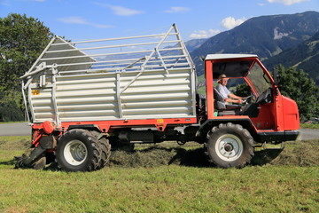 Obraz premium Landwirt Bergbauer Bauer sitzt in einer Erntemaschine Ladewagen