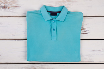 Blue polo t-shirt on wooden background.