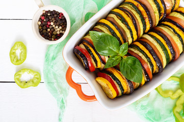 Ratatouille - vegetable dish of zucchini, tomatoes, eggplant slices in ceramic form on a white...