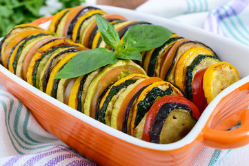 Ratatouille - vegetable dish of zucchini, tomatoes, eggplant slices in ceramic form on a white...