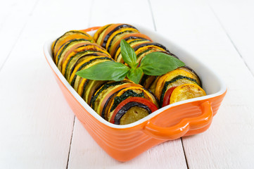 Ratatouille - vegetable dish of zucchini, tomatoes, eggplant slices in ceramic form on a white...