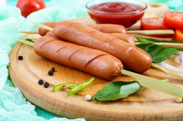 Juicy sausages on skewers with tomatoes and tomato sauce on a round board on a bright background. Top view.
