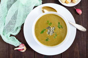 Vegetable cream soup with spinach and potatoes in a white bowl with garlic croutons on a dark wooden background. Dietary vegetarian menu. Proper nutrition.