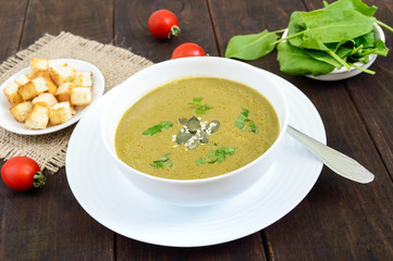 Vegetable cream soup with spinach and potatoes in a white bowl with garlic croutons on a dark wooden background. Dietary vegetarian menu. Proper nutrition.