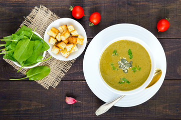 Vegetable cream soup with spinach and potatoes in a white bowl with garlic croutons on a dark wooden background. Dietary vegetarian menu. Proper nutrition.