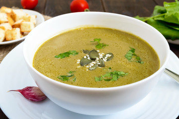 Vegetable cream soup with spinach and potatoes in a white bowl with garlic croutons on a dark wooden background. Dietary vegetarian menu. Proper nutrition.