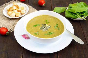 Vegetable cream soup with spinach and potatoes in a white bowl with garlic croutons on a dark wooden background. Dietary vegetarian menu. Proper nutrition.