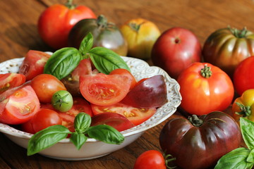 Colorful tomatoes salad with basil and balsamic vinegar on wooden rustic background