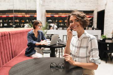 Side view of Smiling curly woman talking by the smartphone