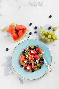 Fresh watermelon salad with feta cheese and berries on white stone table. Top view. Space for text