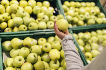 Beautiful woman choosing apples in supermarket.