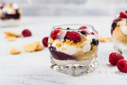 Homemade dessert in glass jars. Cheesecake, trifle, mouse on white wooden background. Copy space