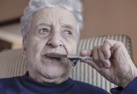 Senior Woman Eating A Chocolate Bar