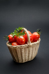 Tomatoes in a wicker basket on gray background