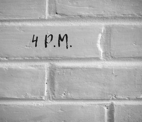 PHOTO OF 4 P.M. WRITTEN ON WHITE PLAIN BRICK WALL