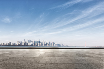 Obraz premium empty marble floor near water with cityscape of modern city