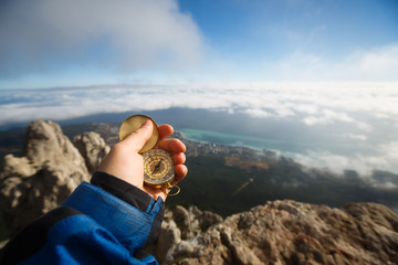 Point of view photo of explorer man searching direction with golden compass in his hand above...