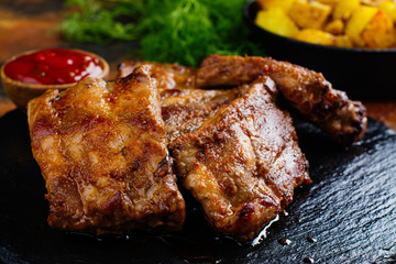 BBQ pork ribs and golden potato wedges. Copy space