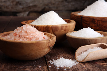 sea salt in bowl. Crystals of salt on table and himalayan salt - obrazy, fototapety, plakaty