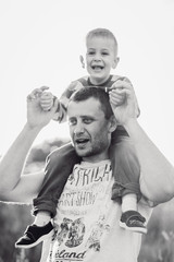 Cheerful little child sits on father's neck