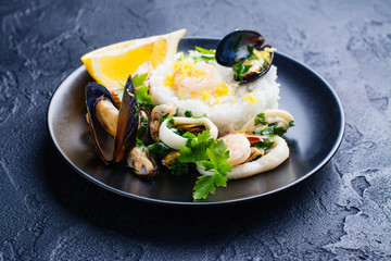 Seafood saute with rice on black stone table