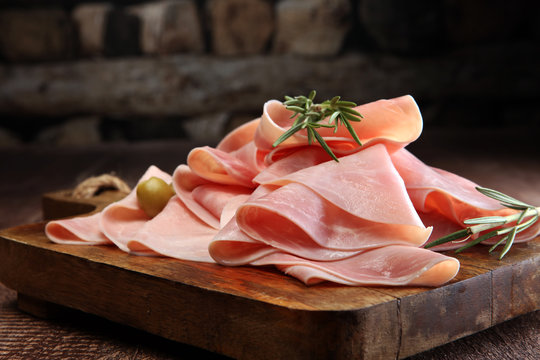 Sliced ham on wooden background. Fresh prosciutto. 