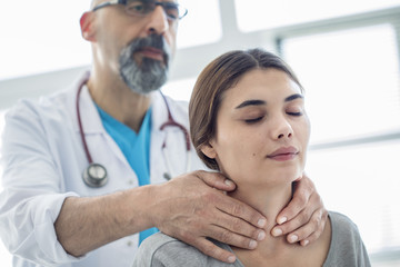 Fototapeta premium Doctor touching throat of patient