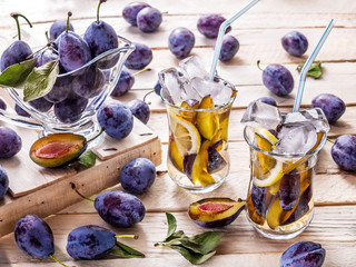 Drink from fresh plums on a wooden background with a glass goblet