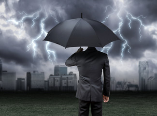 businessman hold umbrella under rain storm with city background