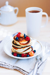 Breakfast, lush pancakes with fresh berries, raspberries and blueberries and a cup of tea