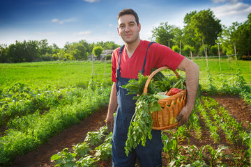 Happy famer holding basket with vegetables