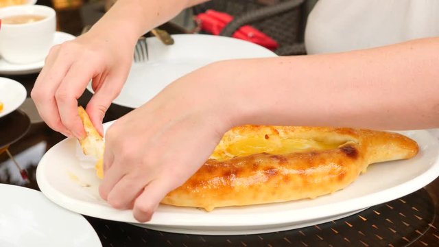 georgian khachapuri megruli with cheese. Someone takes a piece of khachapuri from a plate. Slow motion. 4k